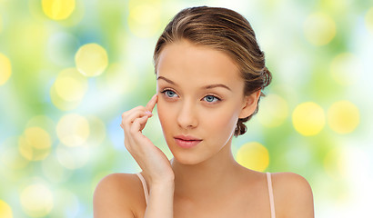 Image showing young woman applying cream to her face