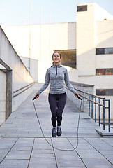 Image showing happy woman exercising with jump-rope outdoors