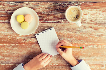 Image showing close up of hands, notebook, coffee and cookies