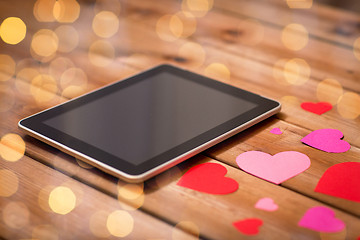 Image showing close up of tablet pc and hearts on wood