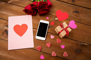 Image showing close up of smartphone, gift, red roses and hearts