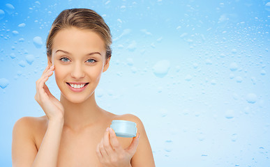 Image showing happy young woman applying cream to her face