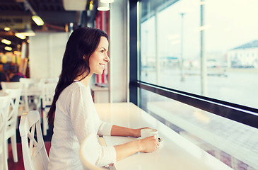 Image showing smiling young woman drinking coffee at cafe