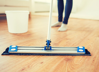 Image showing close up of woman with mop cleaning floor at home