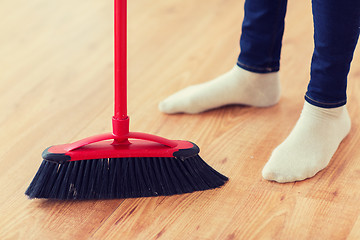 Image showing close up of woman legs with broom sweeping floor