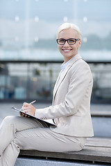 Image showing young smiling businesswoman with notepad outdoors