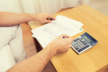 Image showing close up of man with papers and calculator at home