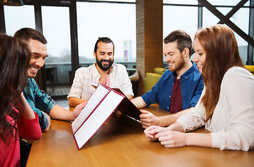 Image showing smiling friends discussing menu at restaurant