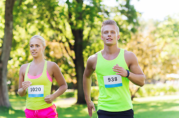 Image showing happy sportsmen couple racing wit badge numbers