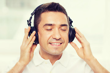 Image showing happy man in headphones listening to music at home