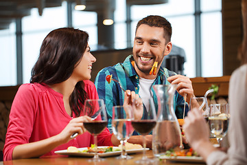 Image showing happy couple with friends eating at restaurant