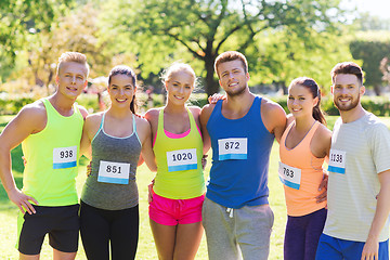 Image showing happy friends or couple with racing badge numbers