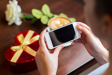 Image showing close up of hands with smartphone, gift and coffee
