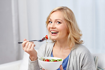 Image showing smiling middle aged woman eating salad at home