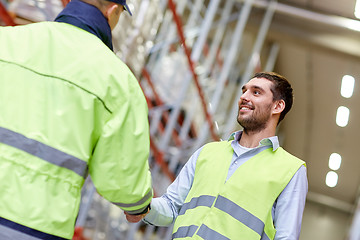 Image showing men in safety vests shaking hands at warehouse