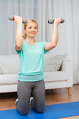 Image showing woman exercising with dumbbells on mat at home