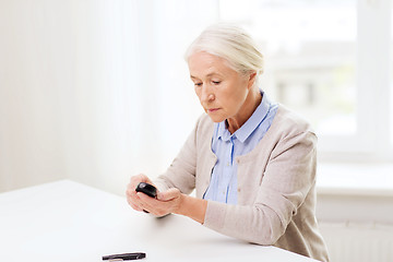 Image showing senior woman with glucometer checking blood sugar