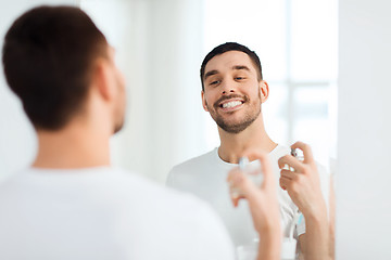 Image showing man with perfume looking to mirror at bathroom