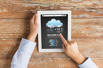 Image showing close up of hands with weather cast on tablet pc