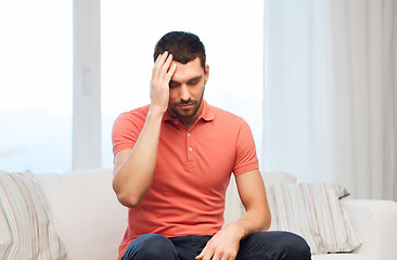 Image showing unhappy man suffering from headache at home