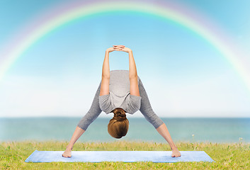 Image showing woman making yoga wide-legged forward bend on mat