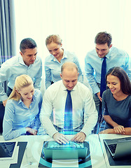 Image showing smiling business people with laptop in office