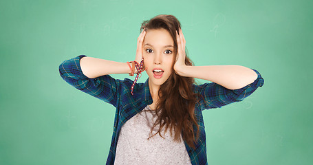 Image showing happy pretty teenage student girl holding to head