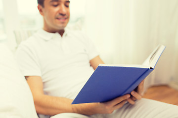 Image showing close up of happy man reading book at home