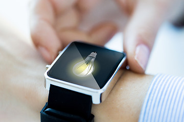 Image showing close up of hands with lightbulb on smartwatch