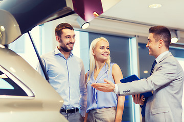 Image showing happy couple with car dealer in auto show or salon