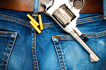 Image showing revolver with cartridges on old blue jeans