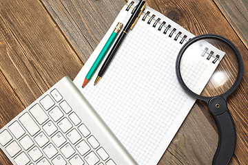 Image showing notebook, computer keyboard, magnifying glass and a pencil with 