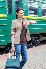 Image showing beautiful woman looks at his watch on the platform of the railwa