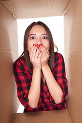 Image showing Girl opening a carton box and looking inside