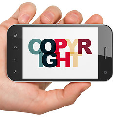 Image showing Law concept: Hand Holding Smartphone with Copyright on  display