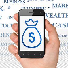 Image showing Banking concept: Hand Holding Smartphone with Money Bag on display