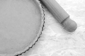 Image showing Baking tin lined with pastry, wooden rolling pin beside