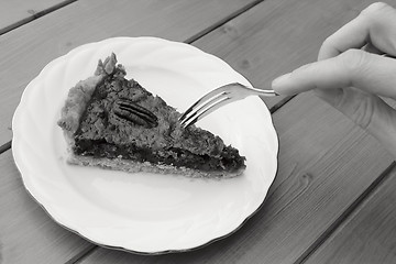 Image showing Woman uses dessert fork to cut into a slice of pecan pie