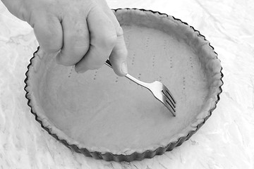 Image showing Woman using fork to prick holes in an uncooked pie crust