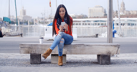 Image showing Young woman sitting on a bench in town