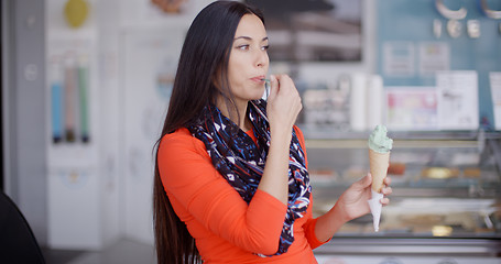 Image showing Smiling young woman savoring an ice cream cone