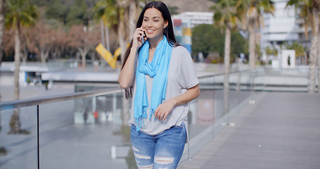 Image showing Woman walking along a promenade with mobile