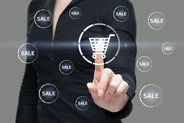 Image showing Beautiful Woman Pointing at Glowing Shopping Cart Icon. Business Concept. button sale