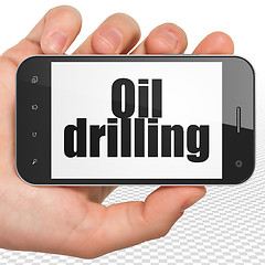 Image showing Industry concept: Hand Holding Smartphone with Oil Drilling on display