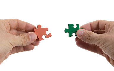 Image showing Close-up of hands trying to connect big jigsaw puzzle pieces