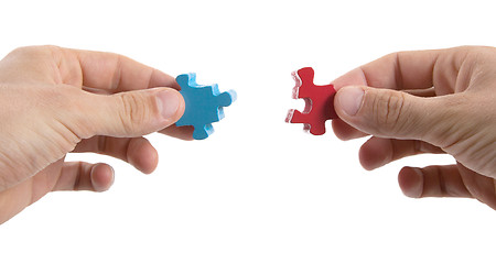 Image showing Close-up of hands trying to connect big jigsaw puzzle pieces