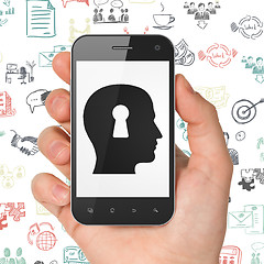 Image showing Finance concept: Hand Holding Smartphone with Head With Keyhole on display