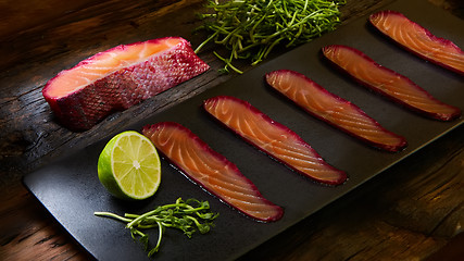 Image showing Sliced salmon fillet, sauteed with beetroot juice over black slate surface.