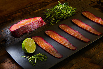 Image showing Sliced salmon fillet, sauteed with beetroot juice over black slate surface.