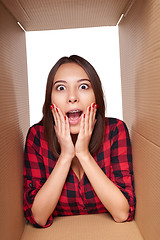 Image showing Girl opening a carton box and looking inside